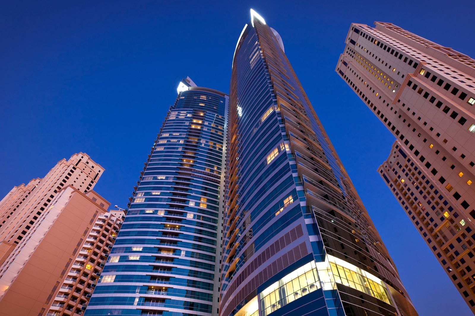 few skyscrapers as seen from below soaring high with the night sky in the background - Rhythm Gurugram