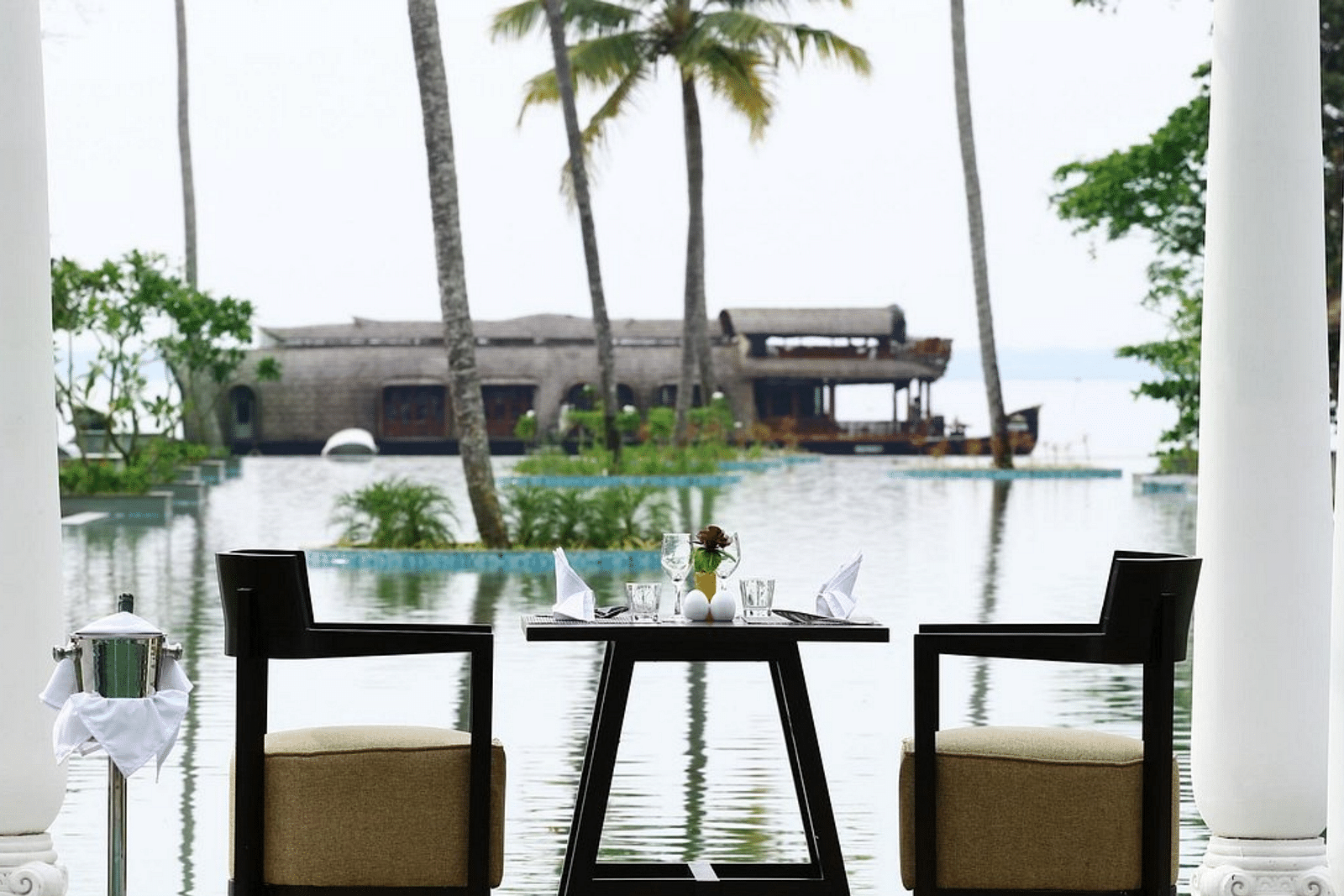 Seating arrangement in front of the pool with a coconut trees in view - Rhythm Kumarakom.