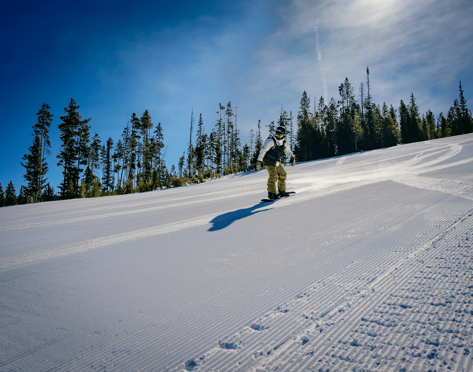 A person skiing on a snow covered mountain with pine trees surrounding it.