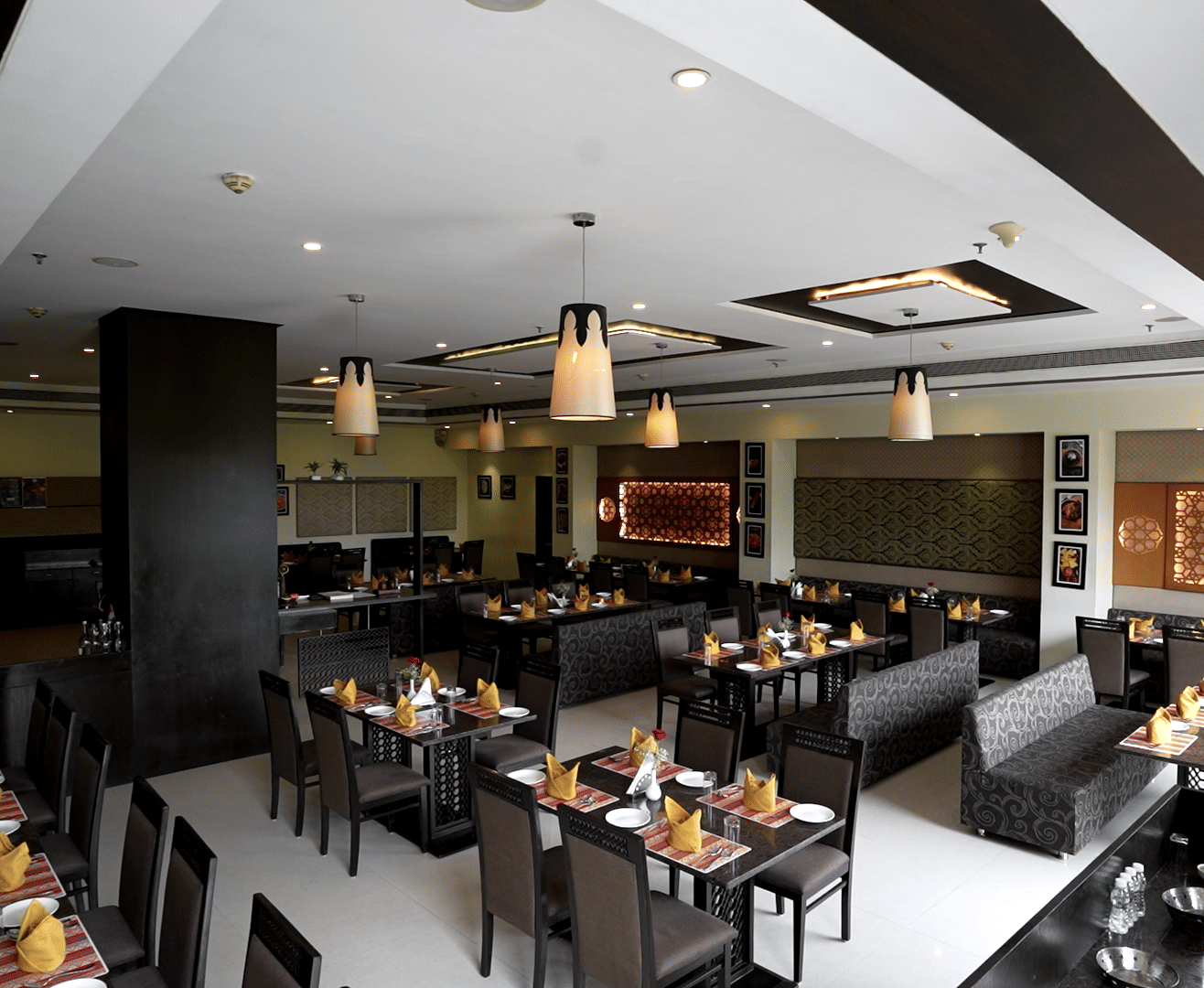 Elegant restaurant with neatly arranged tables and modern decor at Narayani Heights Hotel & Resorts, Ahmedabad.