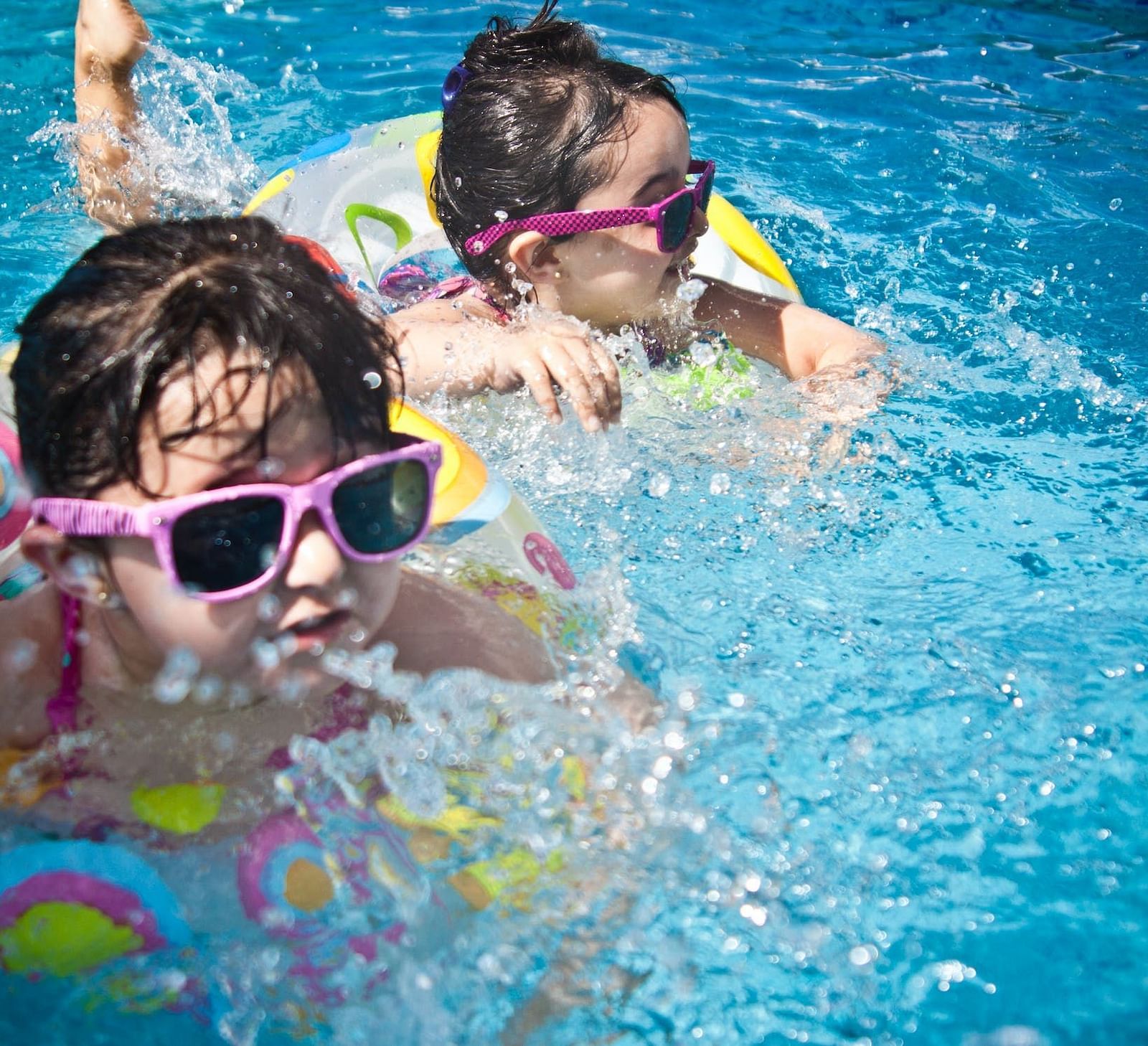 Two children swimming in a pool using floaties
