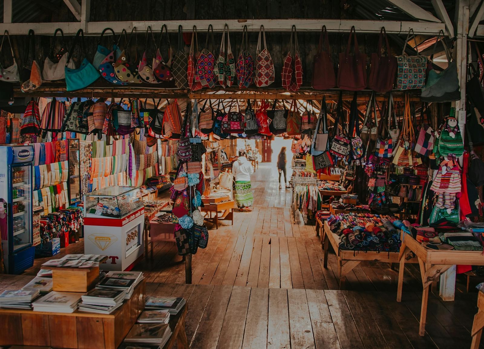 An indoor market with stalls selling colourful fabrics and goods.