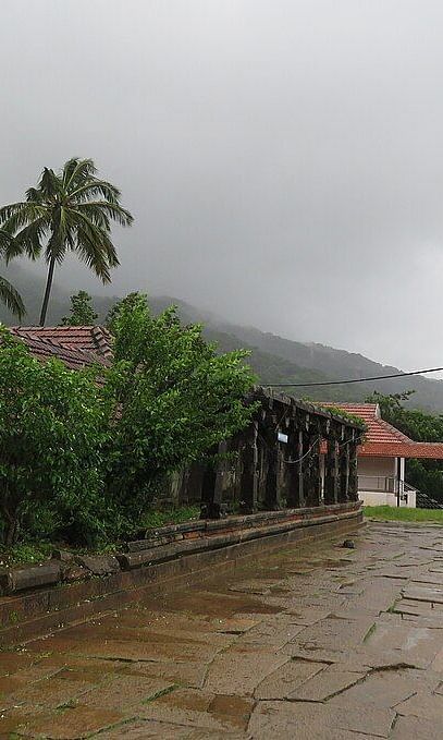A building with a clay tile roof and a stone path with misty hills and greenery all around