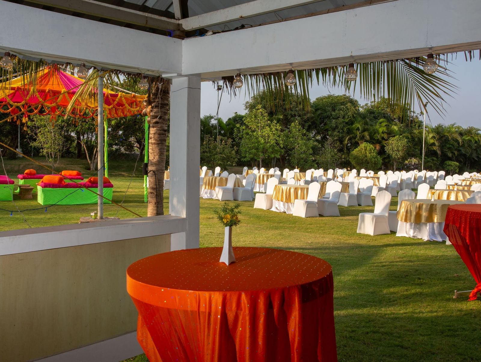 An outdoor event setup with an orange and yellow tent over a table, surrounded by white chairs | Citrus Garden | Grand Bay Resort and Spa
