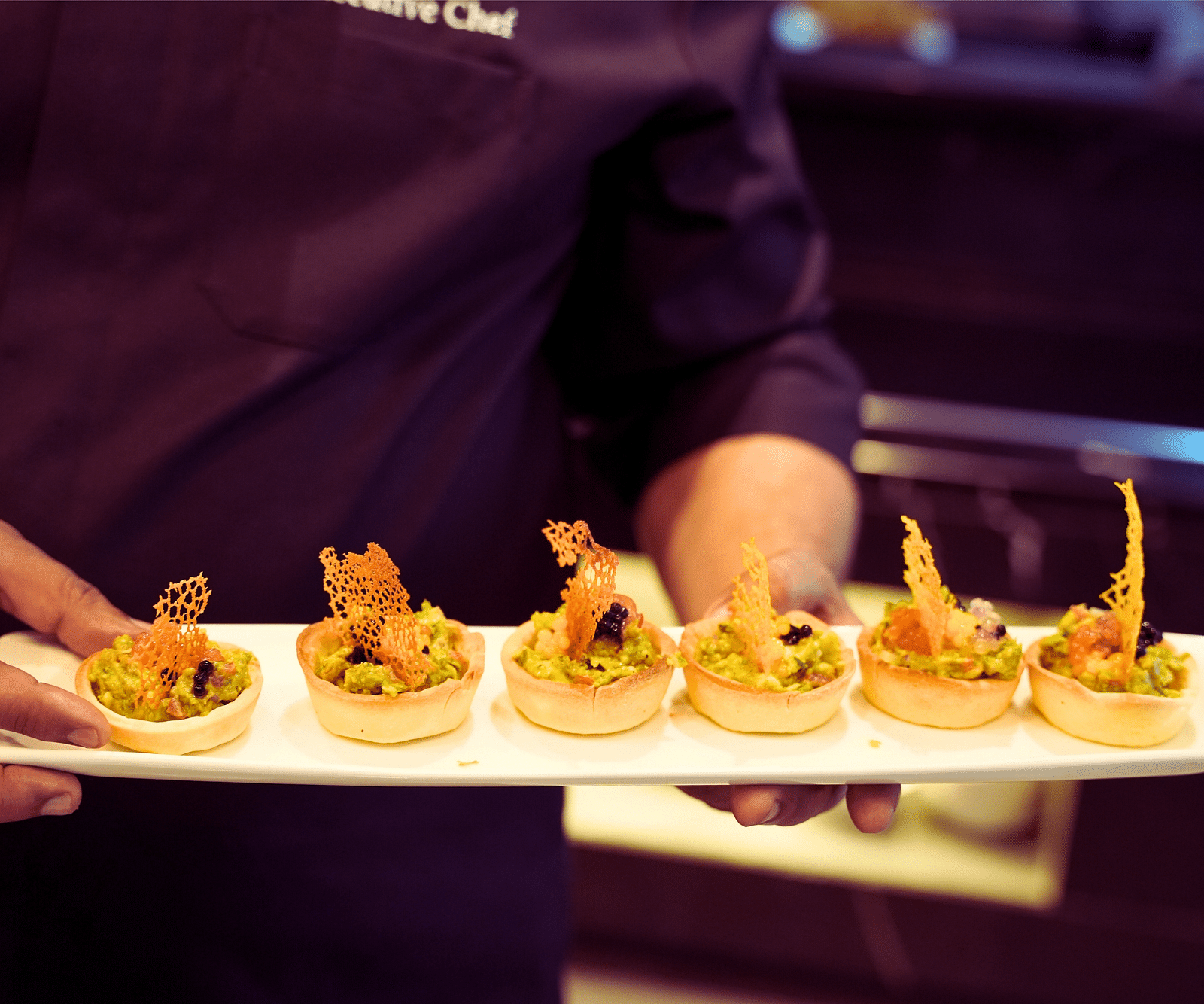 a close up shot of a chef holding a plate of dessert - Rhythm Gurugram