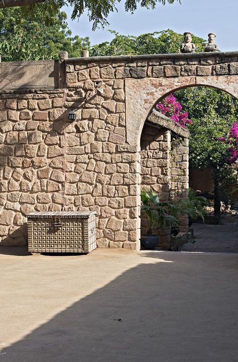 An image of an entrance with a arc shaped gate and lush greenery around - MANVAR Resort & Desert Camp