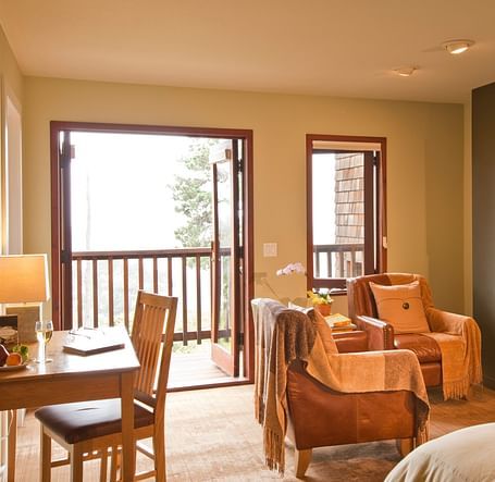 A spacious, elegant hotel room with large windows showcasing beautiful greenery outside, offering a tranquil and inviting atmosphere - Brewery Gulch Inn & Spa