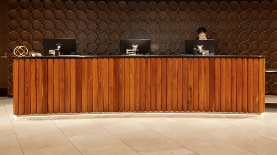 Modern and spacious hotel reception area with a long wooden desk and elegant gold wall panelling.