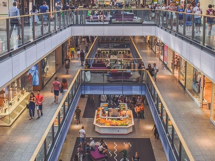 A bustling shopping mall with multiple levels, filled with shoppers and various stores.