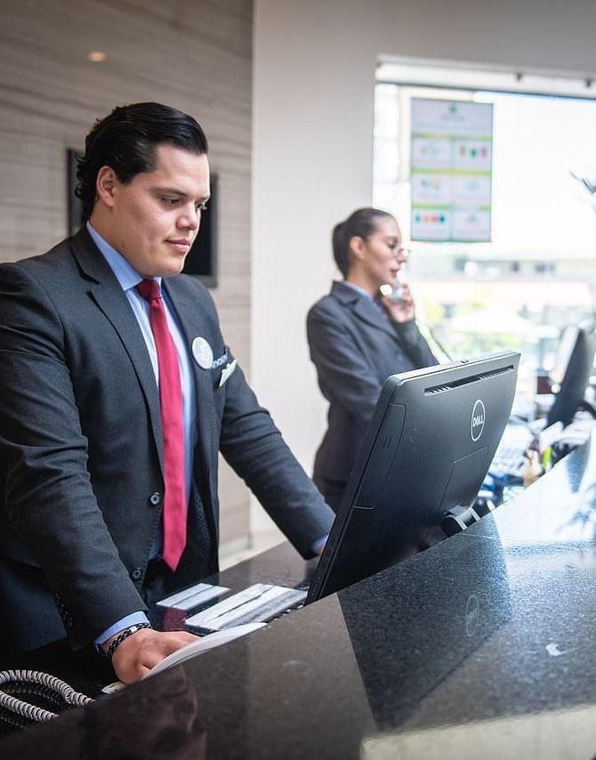 Two staff members standing behind the reception desk dressed in business formals.