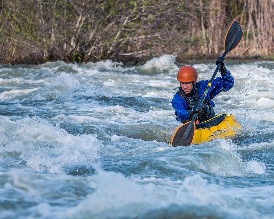 A kayaker rowing on the rough water body
