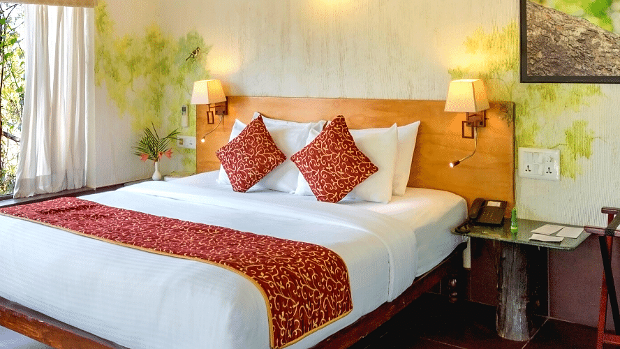 A shot of the bed with bedding in Gardenview Cottage | The Riverwood Forest Retreat, Pench