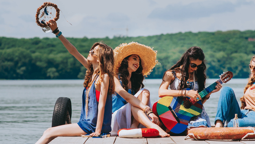 a group of women sun bathing and one girl playing the guitar with the backdrop of a lake - Caravela Beach Resort, Goa