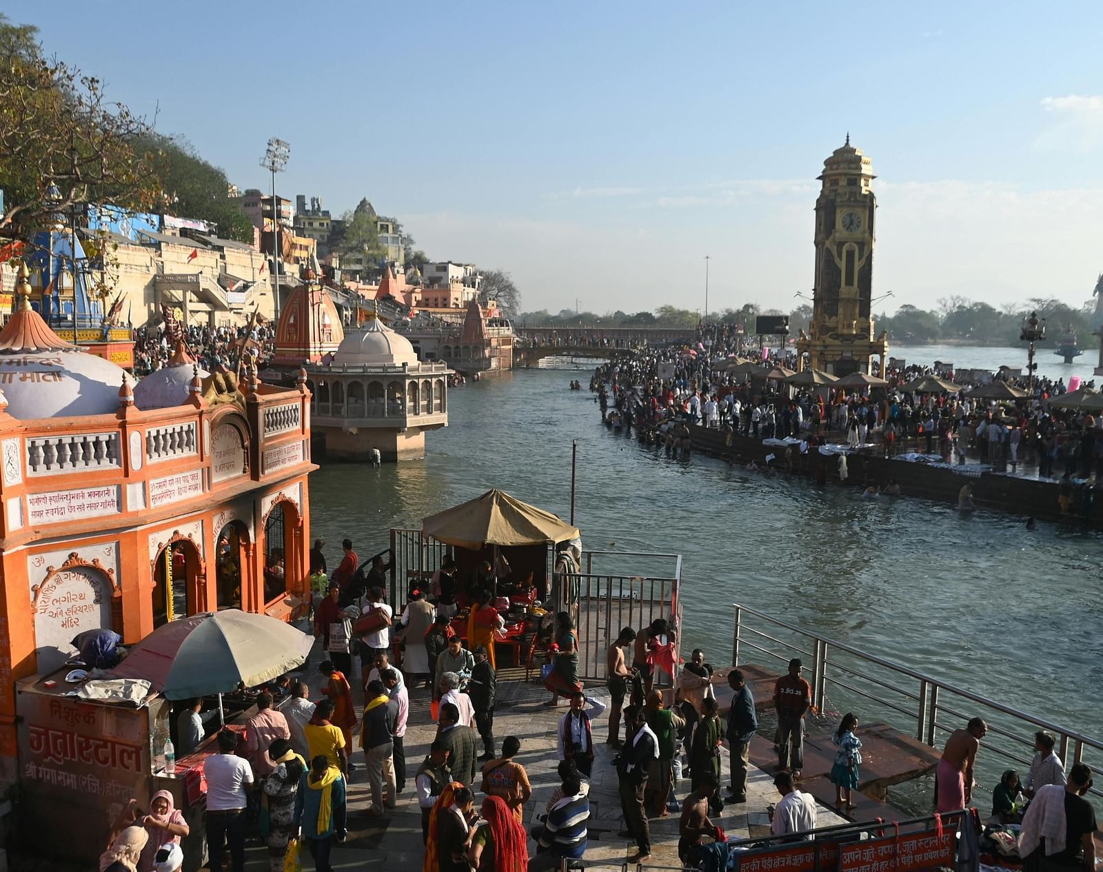 Pilgrims at Har Ki Pauri, Haridwar, participating in a spiritual ritual along the Ganges River near historic temples.