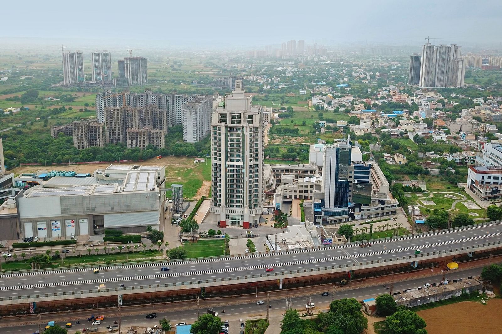 Bird's eye view of Rhythm Gurugram with other buildings and trees next to it 