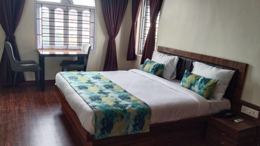A double bed with chairs & study table next to it inside Premium room with balcony