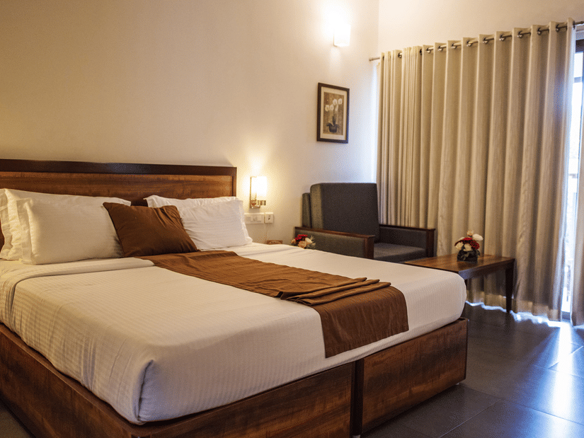 An overview of a room with a king bed, side lamps and tables at Abad Green Forest, Thekkady - The perfect Forest Stay in Kerala.