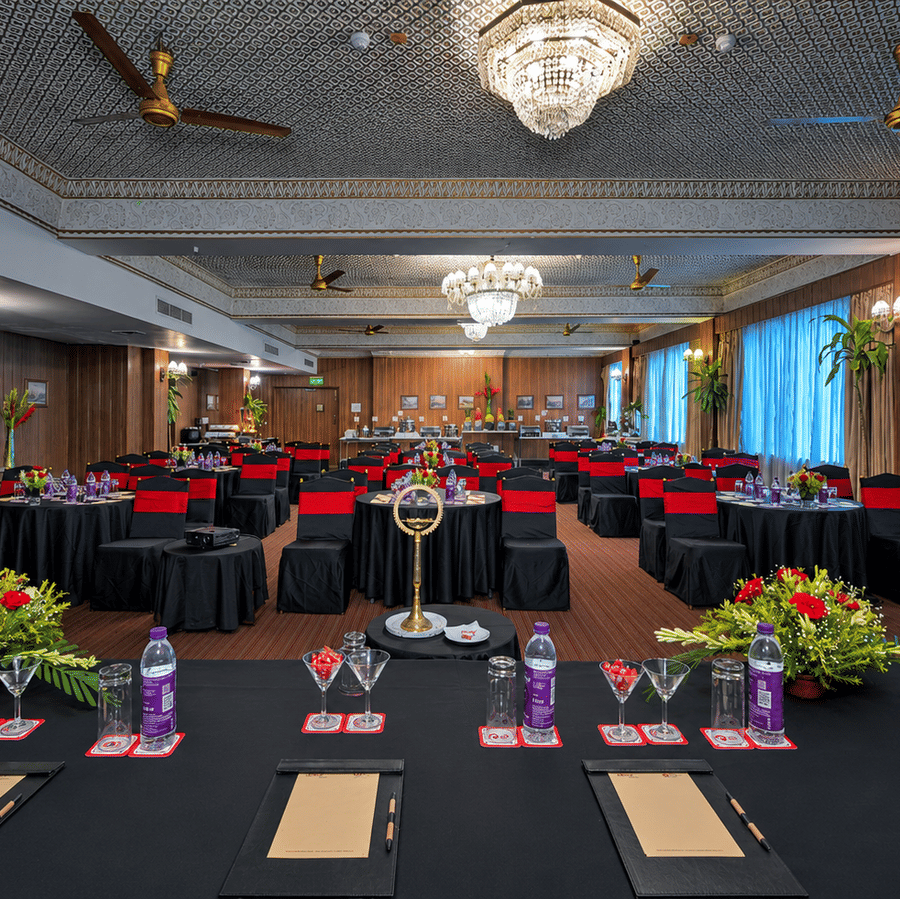 An event hall at Clarks Varanasi, with chairs, tables and chandeliers.