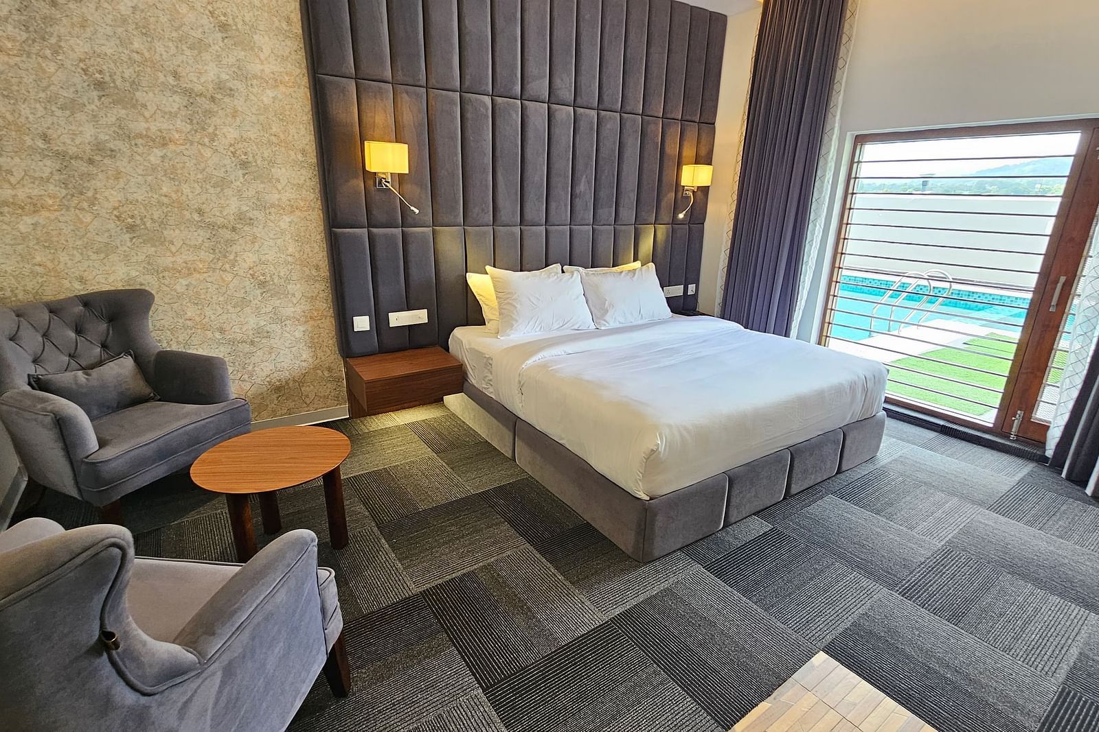 full view image of the premium room at Eminence The Corbett withe a comfortable double bed and huge windows besides it