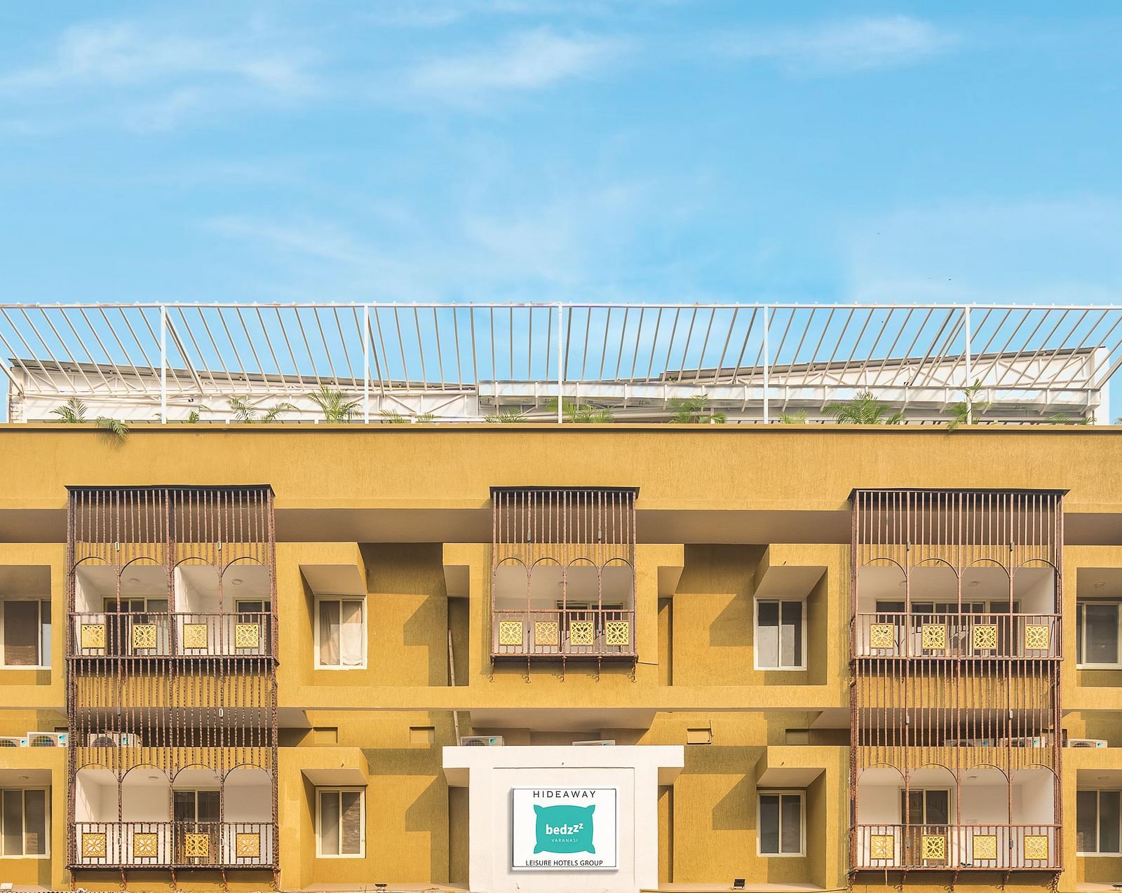 A close image of the front view of Bedzzz Varanasi, captured in daylight, featuring the logo of the property and the roof top area.