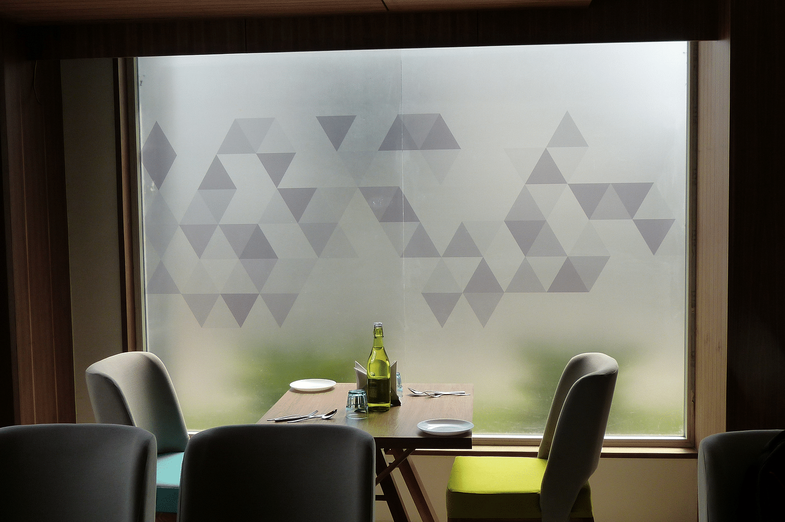 The table is neatly set with cutlery, and two seats are placed on each side, next to the window