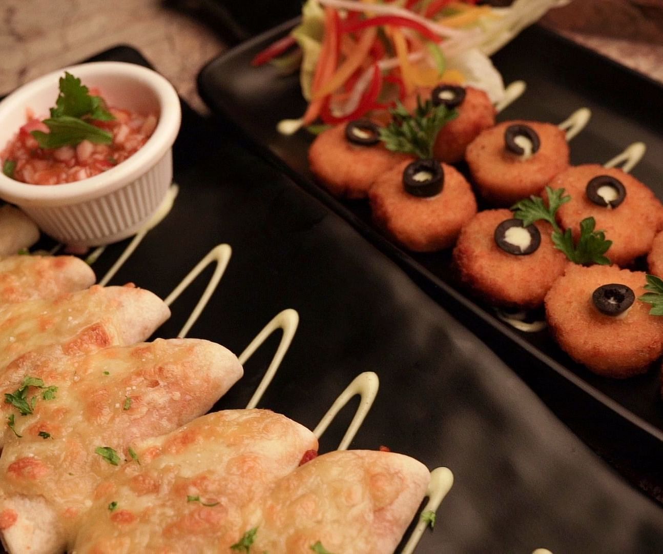 An image of image of cheese balls and fritters served on a trays with dips - Pai Group of Hotels