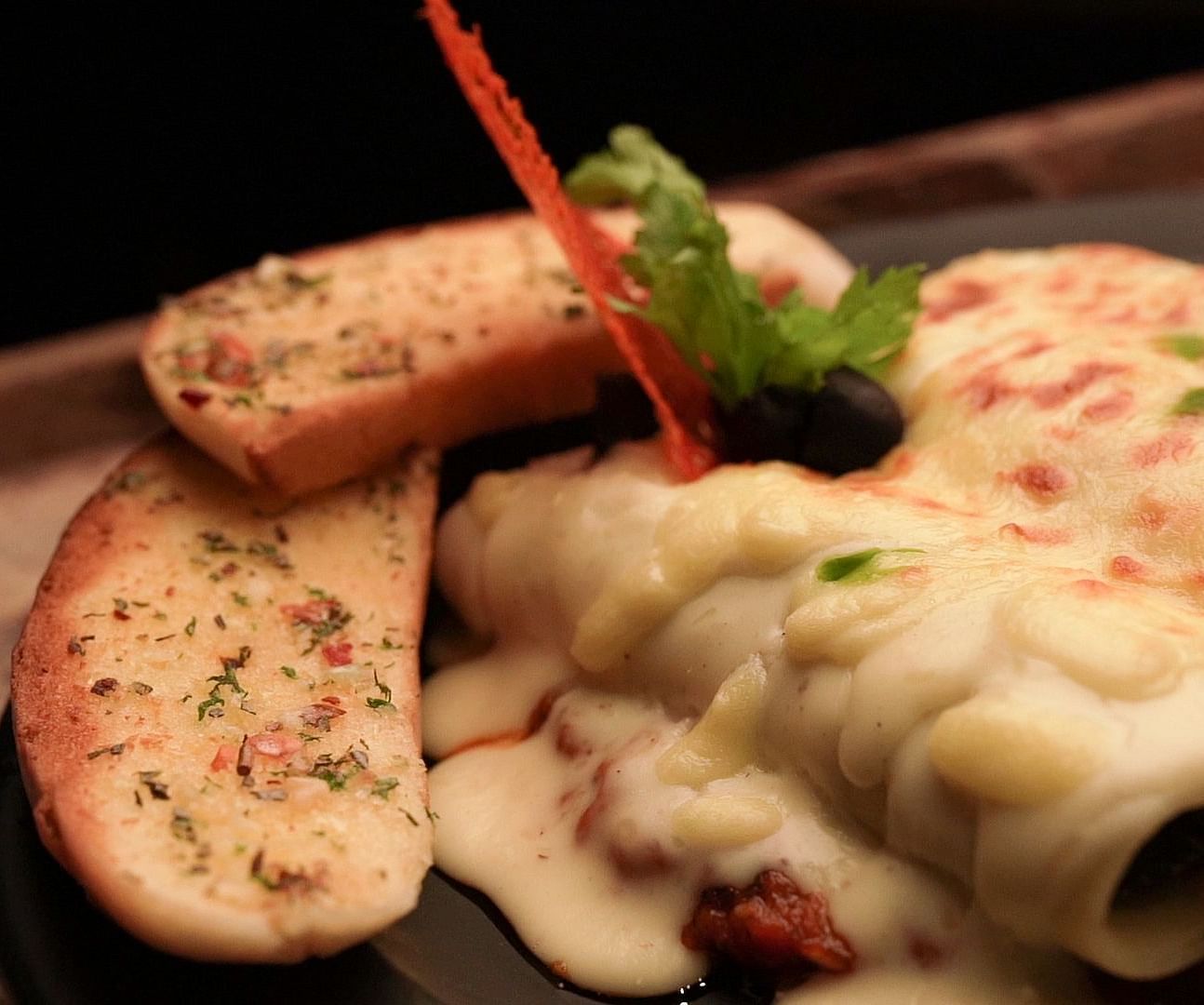 An image of garlic bread with cheese served in a platter - Pai Group of Hotels