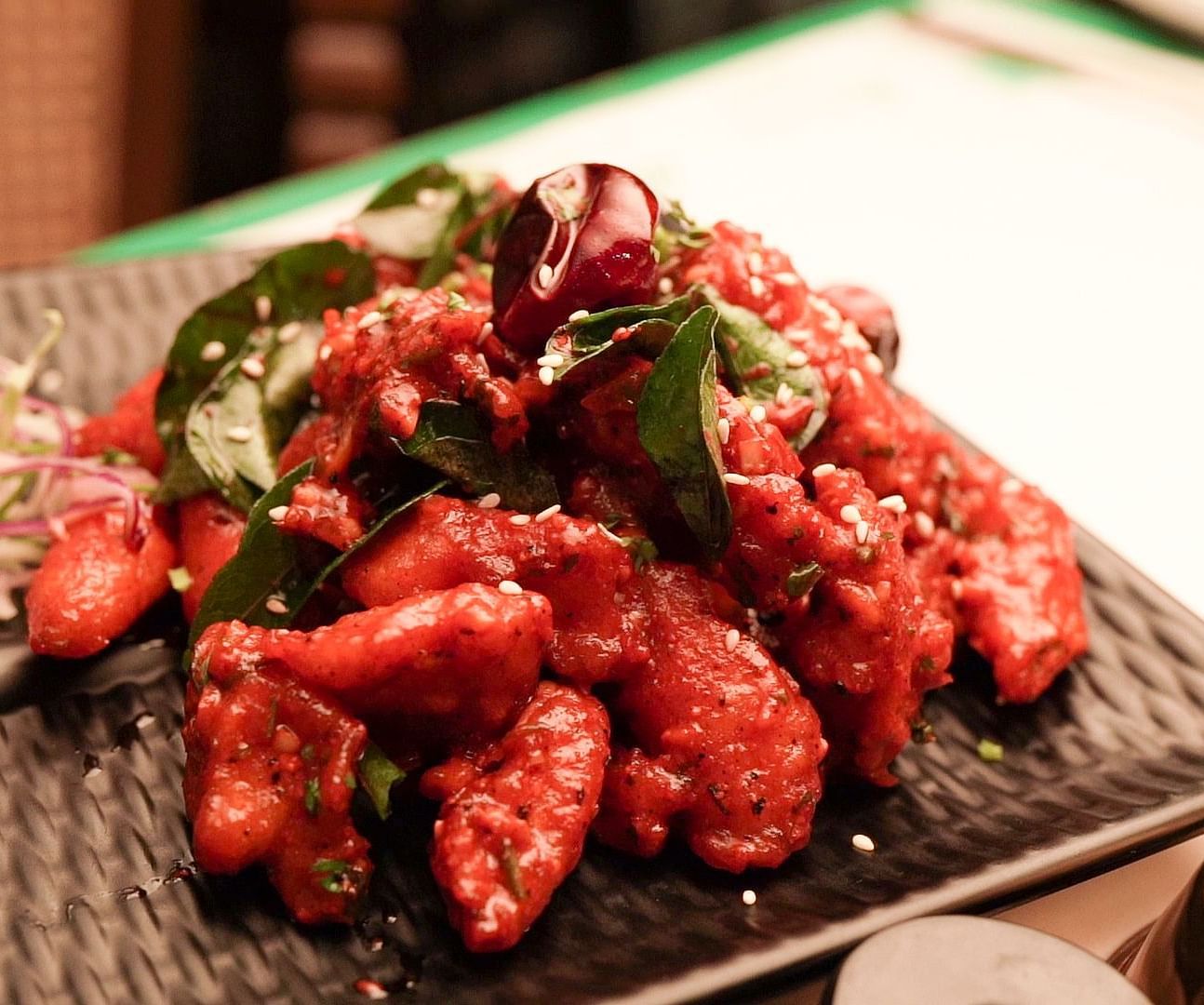 An image of a chicken fry seasoned with curry leaves served in a bowl - Pai Group of Hotels
