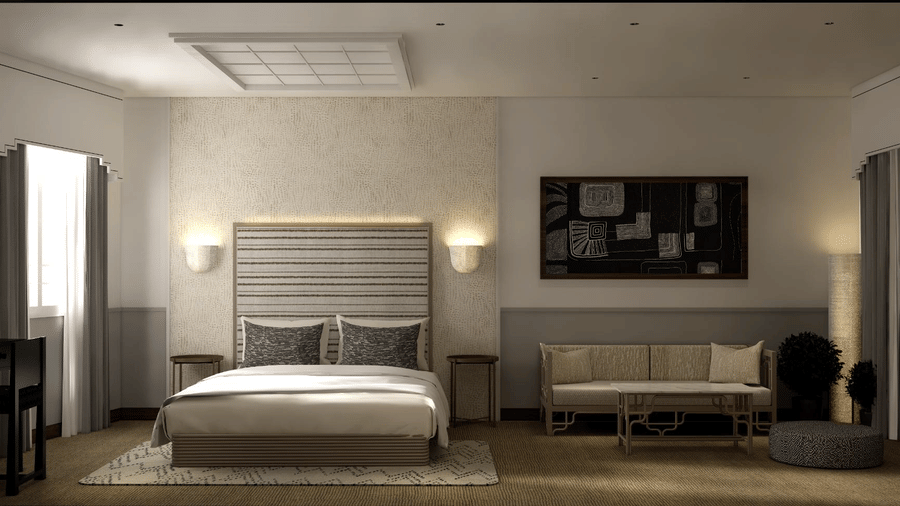 A king size bed with 2 wall lamps, a beige sofa, and a dark armchair in a suite with neutral walls and window at Shilton Suites, Bengaluru.