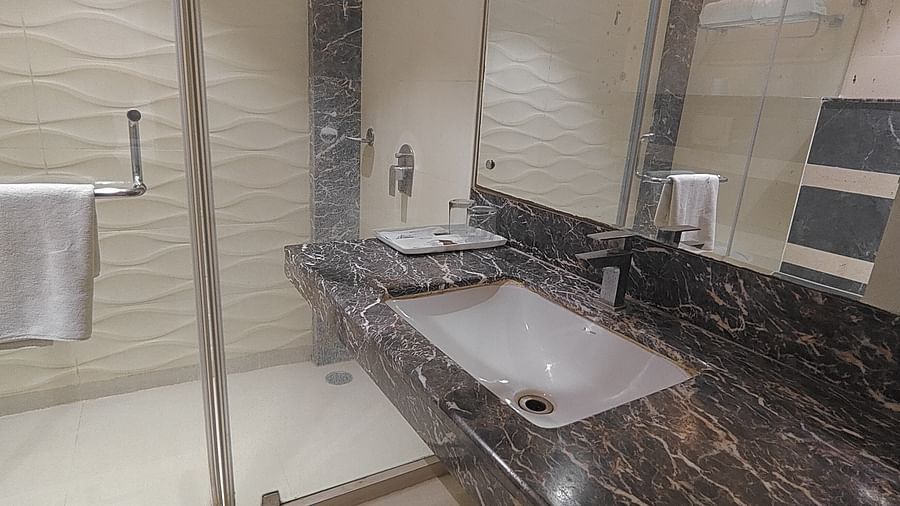 Bathroom interior featuring a sleek countertop and full mirror at Sapna Clarks Inn.