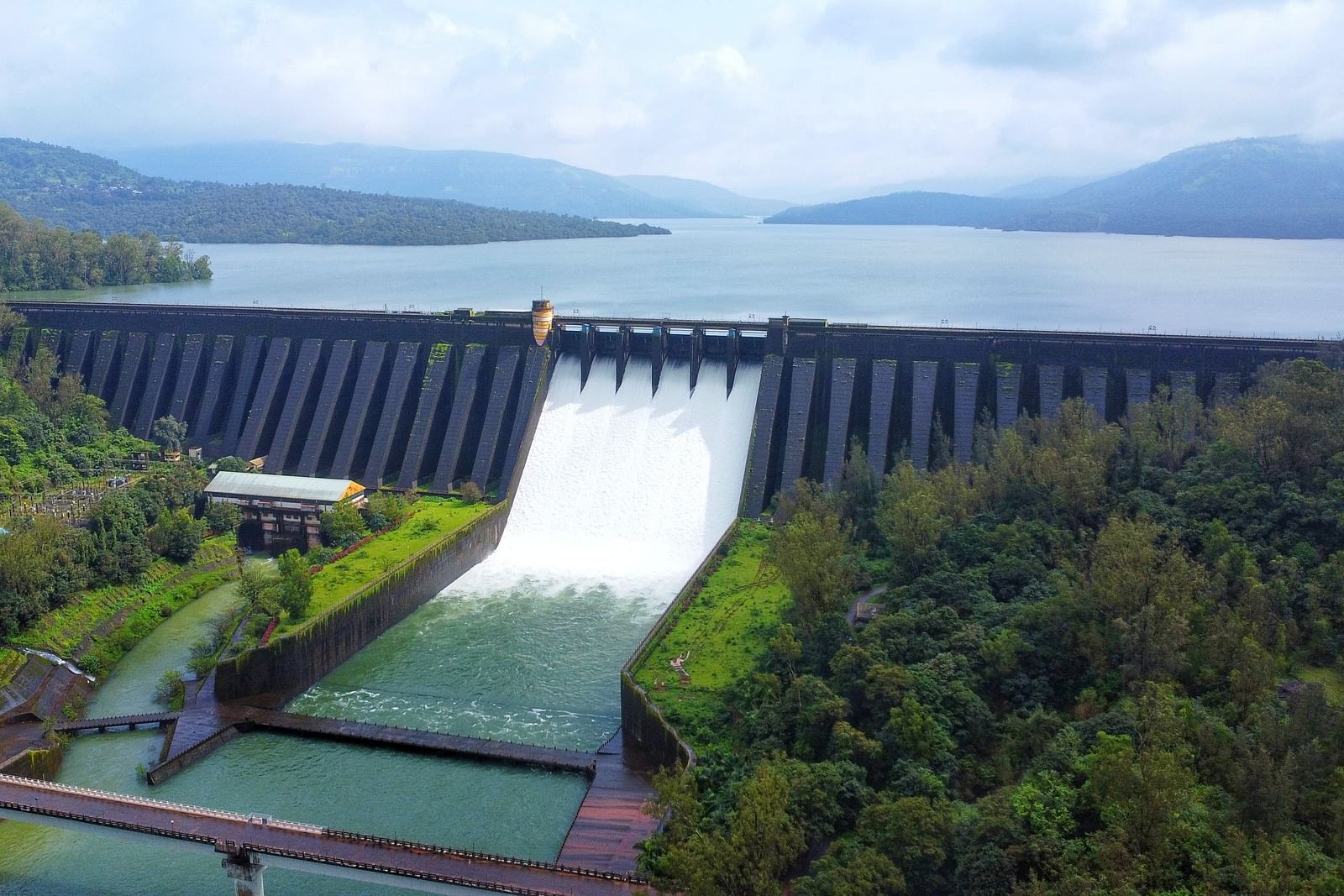The Konya dam releasing water surrounded by forested hills