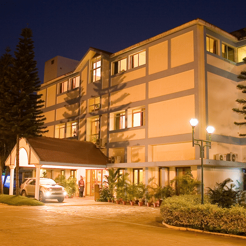 The building exterior of the best resort in Bangalore at night, with lights and pathways | Ramanashree California Resort