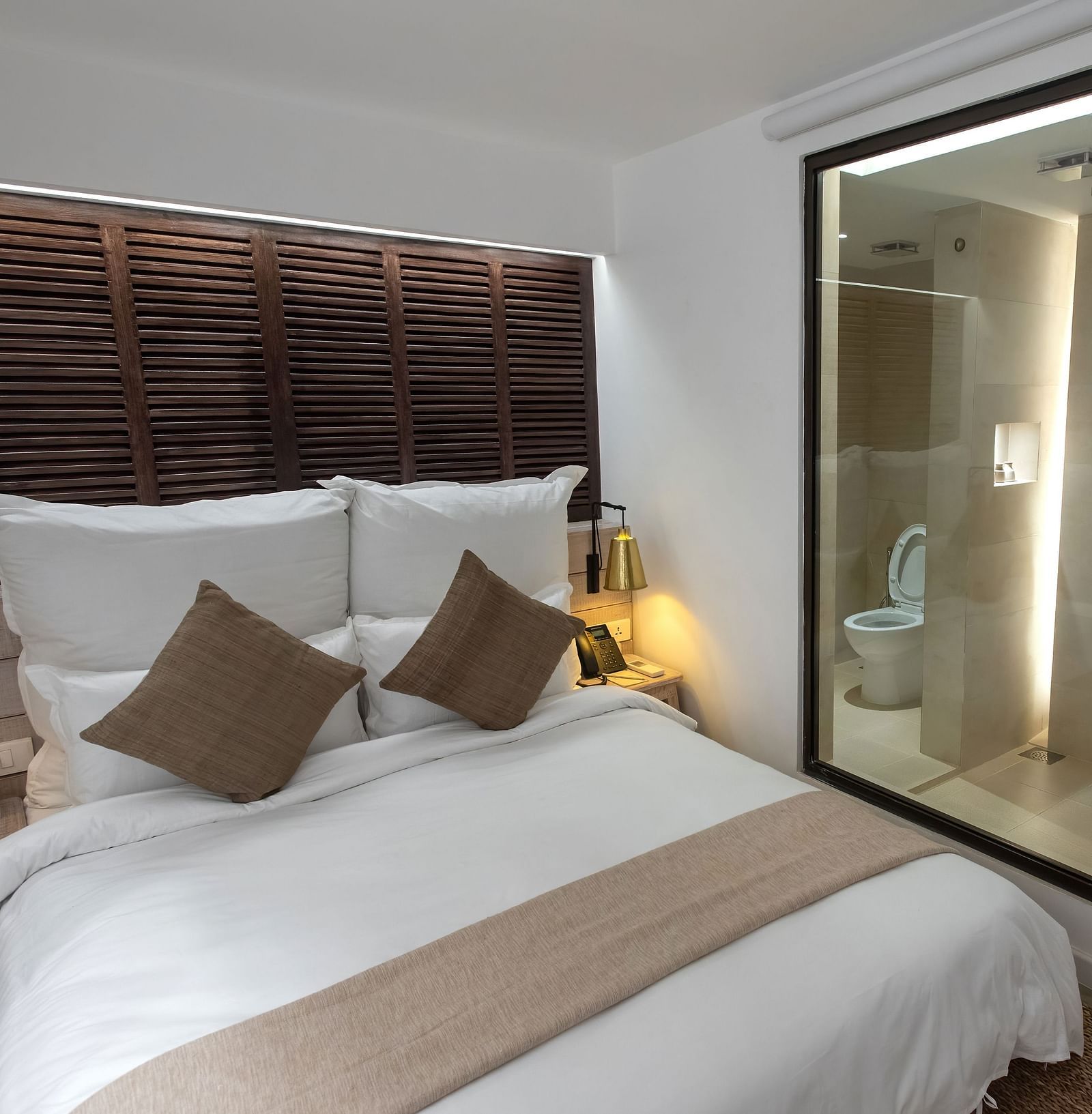 Standard room with a bed, bed side table, lamps and the washroom area - The Nanee