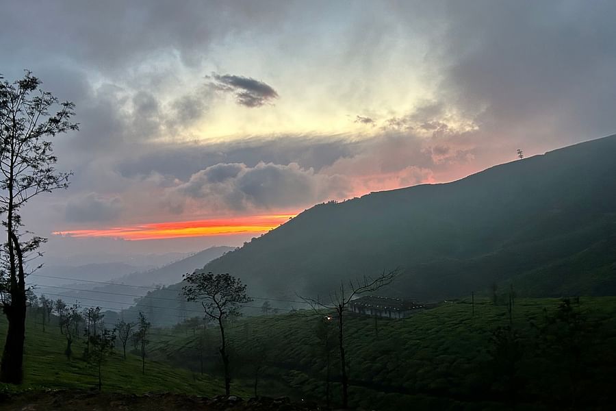 An image of an orange sunset partially hidden by soft, rolling clouds.