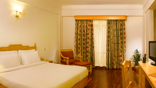 An overview of the Suite at Abad Atrium, MG Road, with a double bed, side tables and lamps in view.