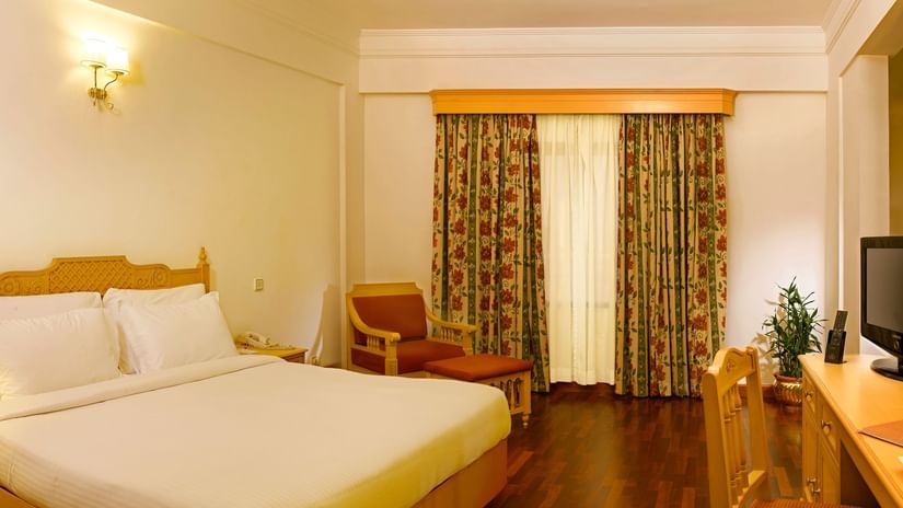 An overview of the Suite at Abad Atrium, MG Road, with a double bed, side tables and lamps in view.