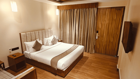 A well-lit bedroom at Red Skin Villa featuring a double bed, wall-mounted TV, and wooden interiors
