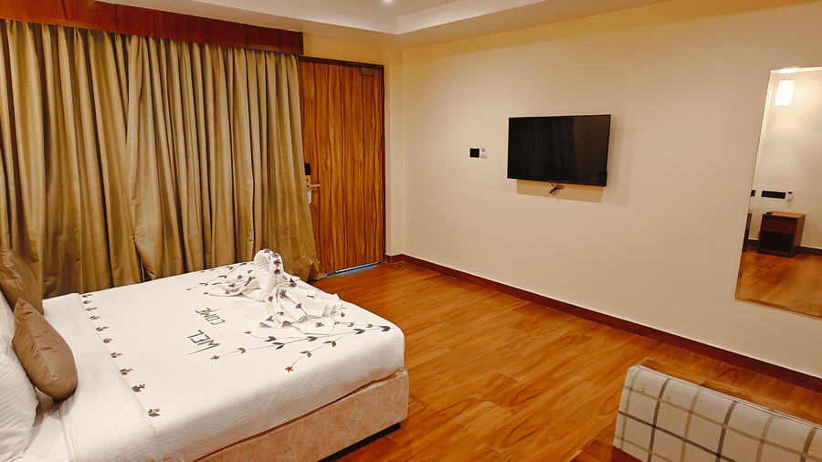 A spacious bedroom at Ross Villa featuring a double bed, wall-mounted TV, and elegant curtains