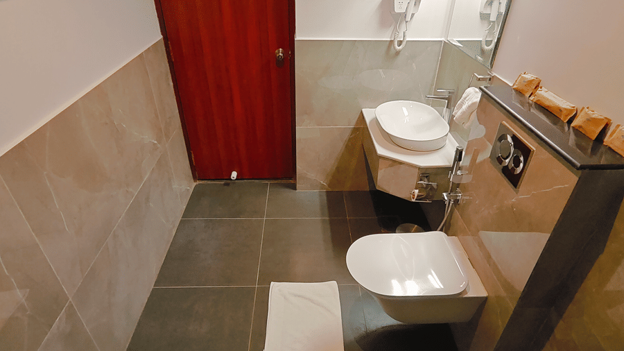 A neatly designed bathroom at Ross Villa with a wall-mounted toilet, washbasin, and mirror