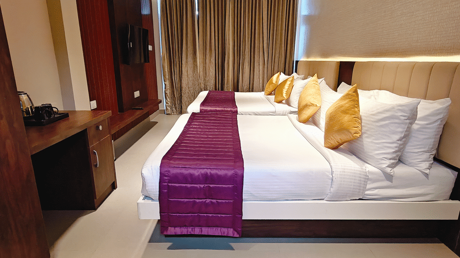 2 beds with white linens and purple runners next to a wooden desk and wardrobe at Bliss Casa Mila By Bergamont Hotels, Kodaikanal.