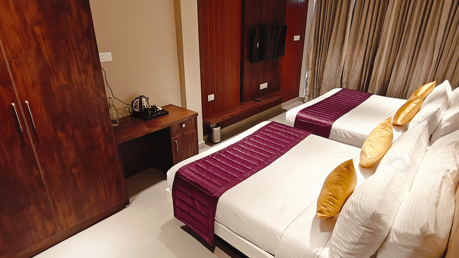 A large wooden wardrobe stands next to a small desk area with a kettle in a room at Bliss Casa Mila By Bergamont Hotels, Kodaikanal.