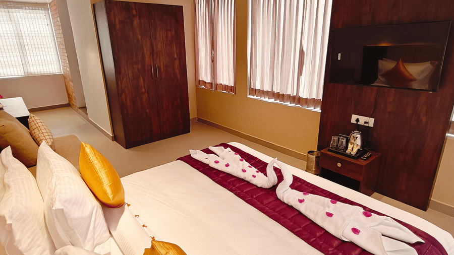 A view from the head of a bed looking towards a dark wooden wardrobe and 2 windows at Bliss Casa Mila By Bergamont Hotels, Kodaikanal.