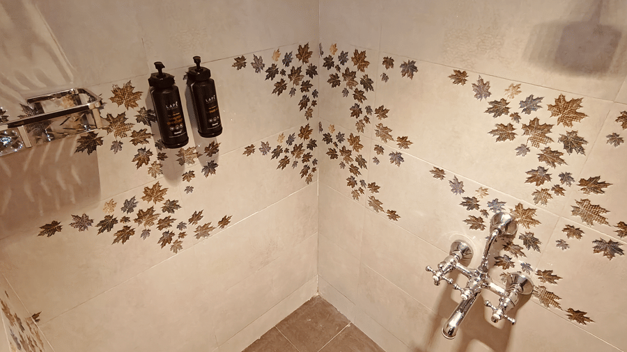 Tiled walls with leaf patterns and chrome shower fittings with wall-mounted bottles at Bliss Casa Mila By Bergamont Hotels, Kodaikanal.