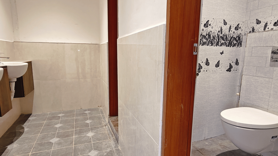 A clean washroom with 2 white sinks and a white wall-mounted toilet at Bliss Casa Mila By Bergamont Hotels, Kodaikanal.