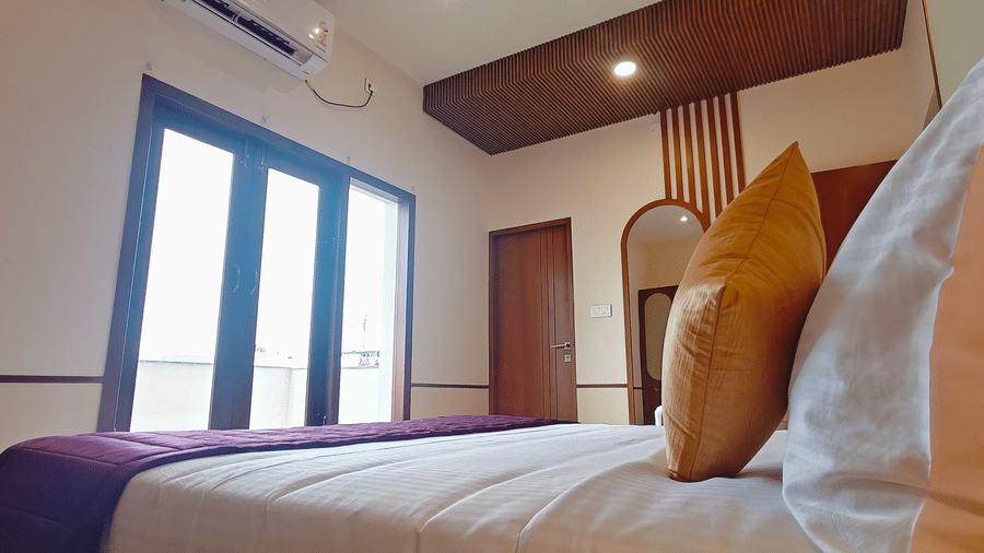 A corner view of a room at Bliss Giriya By Bergamont Tiruvannamalai with a single bed and a French window.