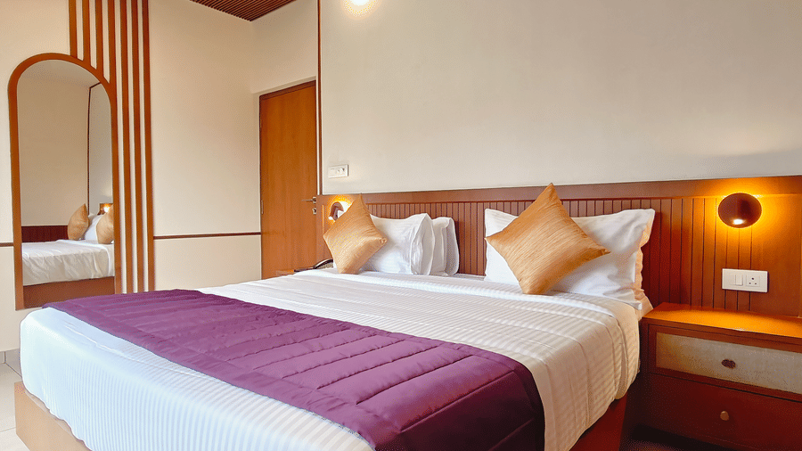 A room at Bliss Giriya By Bergamont Tiruvannamalai with a double bed, full-length mirror, and wooden headboard with reading lights.