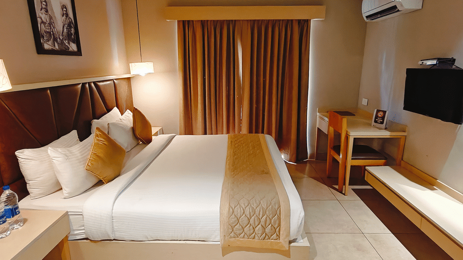 Spacious Deluxe Double Room at Cholaa Dynasty, Kumbakonam featuring a plush double bed with crisp linens, warm ambient lighting, elegant wooden furnishings, and a relaxing atmosphere ideal for a comfortable stay in Kumbakonam