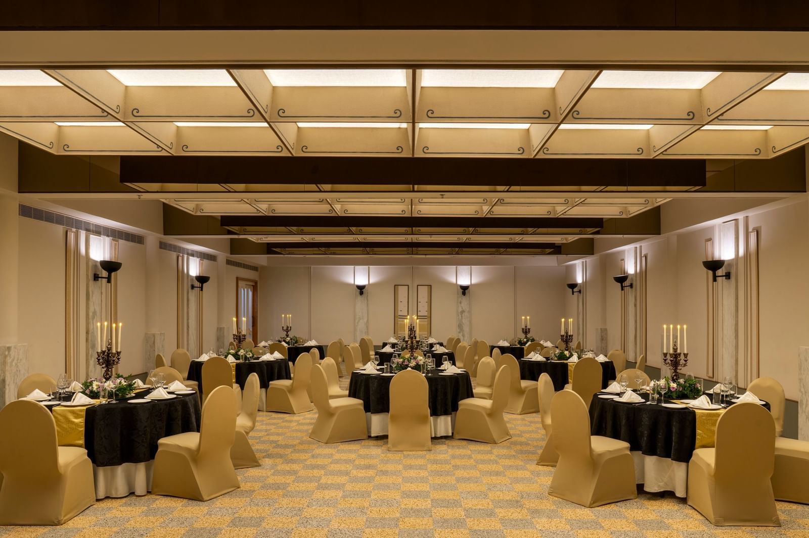  A banquet hall at Shilton International Kochi, set with numerous round tables and chairs, ready for an event.