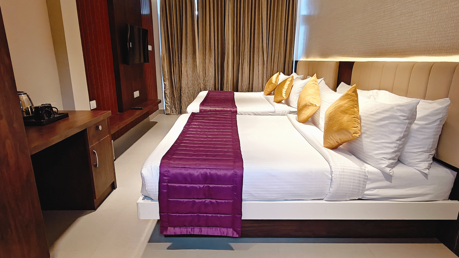 2 beds with white linens and purple runners next to a wooden desk and wardrobe at Bliss Casa Mila By Bergamont Hotels, Kodaikanal.