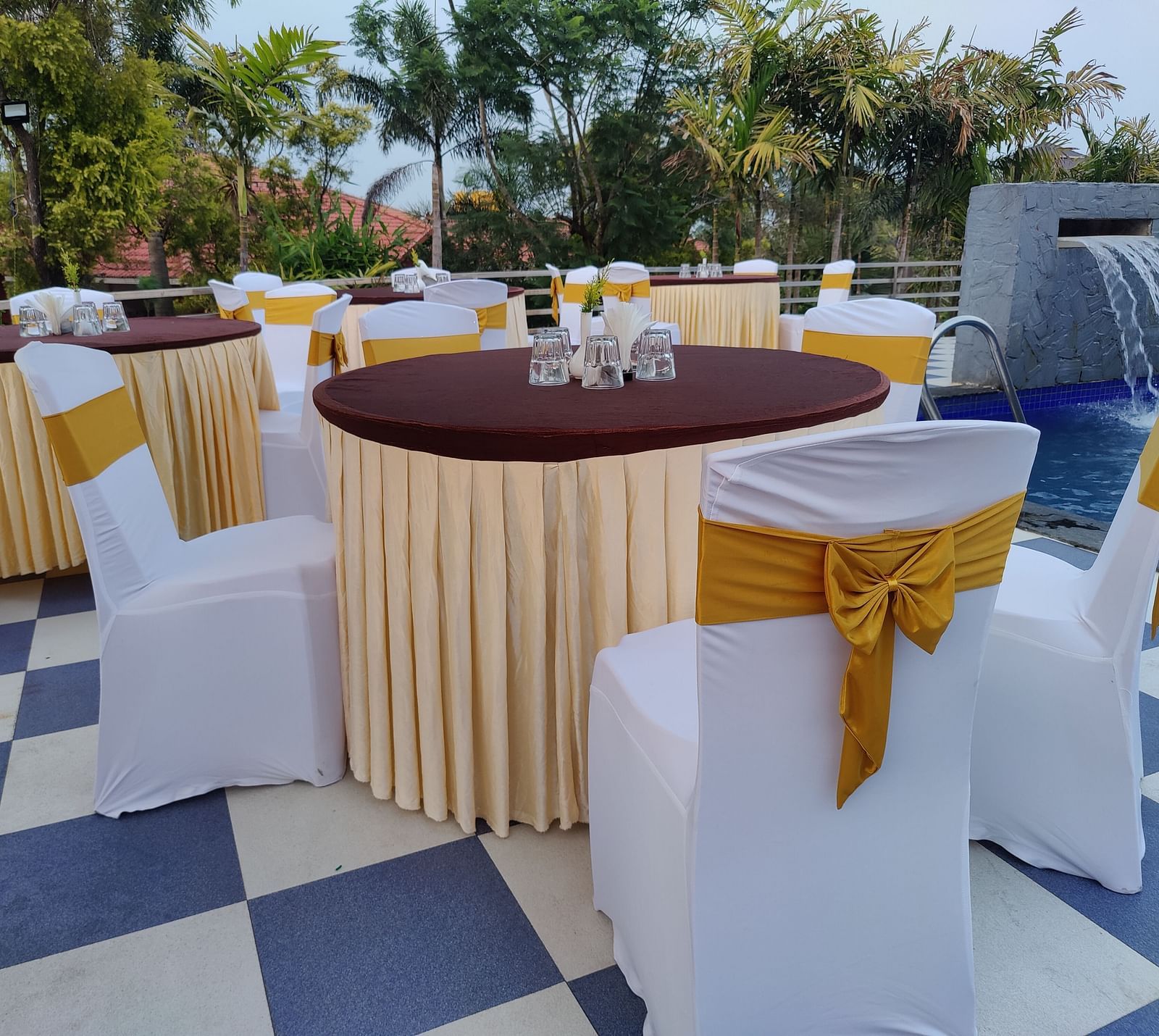 Outdoor event space with round tables and white chair covers | Open Deck | Woodstock Resorts, Coorg